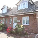 Ein zweistöckiges Haus mit Ziegelfassade und Blumenbeeten vor der Tür.