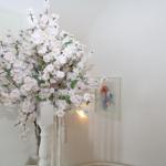 Ein großer weißer Blumenstrauß in einem hohen weißen Vase an der Wand