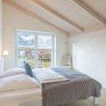 Schlafzimmer mit Bett, Fenster und Holzdach