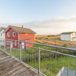 Terrasse mit Blick auf rote und weiße Häuser und Grünflächen.