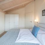 Schlafzimmer mit Bett, Kleiderschrank und Wandbild.