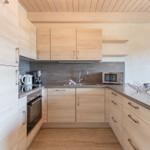 Küche mit Holzmöbeln, Spüle, Herd und Mikrowelle