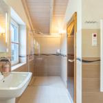 Badezimmer mit Dusche, Waschbecken und Heizkörper.