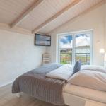Schlafzimmer mit Bett, TV und Fenster zum Balkon.