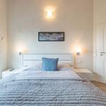 Schlafzimmer mit Bett, Nachttischen und Fenster zur Terrasse.