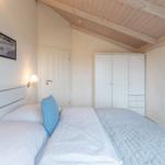 Schlafzimmer mit Doppelbett, Kleiderschrank und Holzdecke.