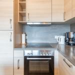 Küche mit Holzschränken, Induktionskochfeld und Kaffeemaschine.