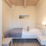 Schlafzimmer mit Bett, Wandlampe und Bild an der Wand.