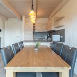 Esszimmer mit Holztisch, Stühlen und Küchenbereich im Hintergrund.