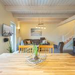 Essbereich mit Holztisch, Wohnbereich mit Sofa und Holzdecke