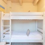 Zimmer mit weißem Doppelstockbett, Holzbalkendecke und Wandbild.