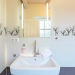Badezimmer mit Waschbecken, Spiegel und Pflanzenmotivfliesen