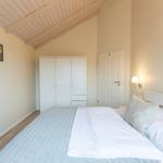 Schlafzimmer mit Doppelbett, Kleiderschrank und Holzdecke.