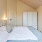 Schlafzimmer mit Bett, Kleiderschrank und Wandbild.