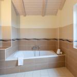 Bad mit Badewanne, Fenster und Holzdecke.