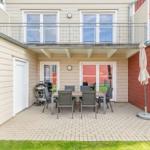 Terrasse mit Tisch, Stühlen, Grill und Sonnenschirm. Obergeschoss mit Balkon.