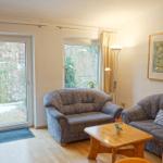 Wohnzimmer mit zwei Sofas, Holztisch und Fenstern zum Garten.