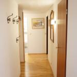 Flur mit Holzboden, Haken, Spiegel und Türen. Bild an der Wand.