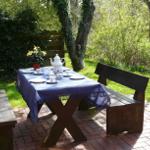 Holztisch mit Tischdecke und Teeservice auf Steinplatten im Garten.
