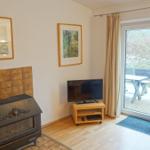 Wohnzimmer mit Kamin, Fernseher und Terrasse.