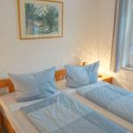 Ein Schlafzimmer mit einem Bett, zwei Nachttischen und einem Fenster mit Blick auf Grün.