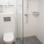 Badezimmer mit Dusche, Toilette und Waschbecken.