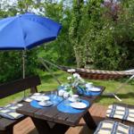 Holztisch mit blauer Sonnenschirm und Hängematten im Garten