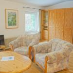 Wohnzimmer mit zwei Sesseln, Couchtisch und TV. Holzmöbel und Fenster zur Außenseite.