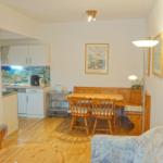 Wohnzimmer mit Essbereich und Küchenbereich. Holzmöbel und Wandbilder.