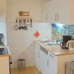 Küche mit Spüle, Kochfeld, Kaffeemaschine und Toaster.