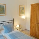 Schlafzimmer mit Bett, Kleiderschrank und Wandbildern.