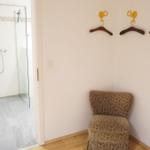 Flur mit Stuhl, Kleiderhaken und Blick in die Dusche.