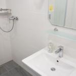 Badezimmer mit Dusche, Waschbecken und Spiegel