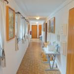 Flur mit Holztüren, Bildern und Fenster mit Pflanze.