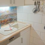 Küche mit Spüle, Geschirrspüler und Wandhalterung für Küchenutensilien.