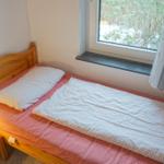 Ein Schlafzimmer mit Holzbett, Nachttisch und Lampe. Fenster mit Blick auf Schnee.