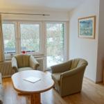 Wohnzimmer mit Sofa, zwei Sesseln, Tisch und Fernseher.