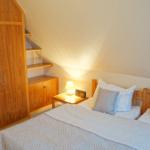 Schlafzimmer mit Doppelbett, Holzschrank und Nachttisch mit Lampe.