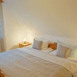 Schlafzimmer mit Holzbett, zwei Nachttischen und Fenster mit Blick auf Bäume.