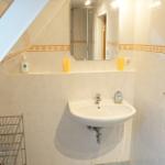 Badezimmer mit Waschbecken, Spiegel und Dusche unter Dachschräge