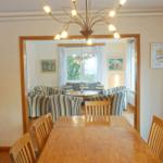 Esszimmer mit Holztisch und Stühlen. Durchgang in Wohnzimmer mit Sofa und Tisch.