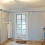 Eingangsbereich mit Glastür, Spiegel und Glas-Tisch mit Blumen.