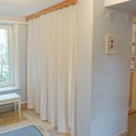 Raum mit Fenster, weiße Bank und Vorhang. Durchgang zu Küche und Schlafzimmer.