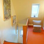 Flur mit Stuhl, Wandbildern und rotem Teppichboden