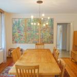 Esszimmer mit Holztisch, Stühlen und Wandbildern. Fenster und Holzfußboden.