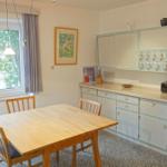 Küche mit Essbereich, Holztisch, Küchenzeile und Fenster.