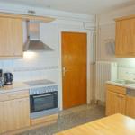 Küche mit Holzschränken, Herd, Spüle und Esstisch.