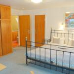 Schlafzimmer mit Bett, Kleiderschrank und Wandbild.