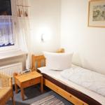 Ein Schlafzimmer mit Bett, Nachttisch, Stuhl und Fenster mit Vorhängen.