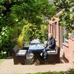 Garten mit Tisch, Bänken und Blühenden Bäumen neben Backsteinhaus